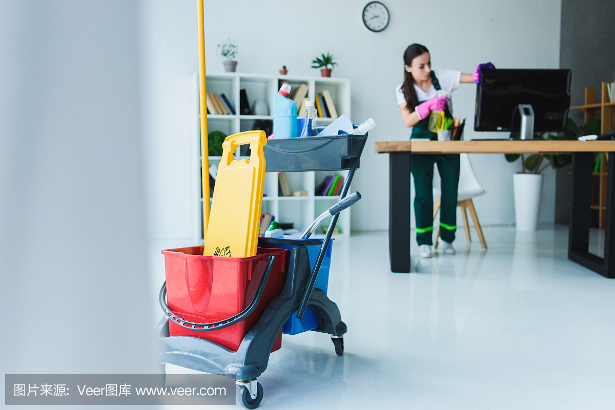 年輕女清潔工用各種清潔設備清潔辦公室